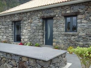 un edificio de piedra con un banco delante en Cottage Quinze, Contemporary designed cottage with Swimming pool, en Ponta Delgada