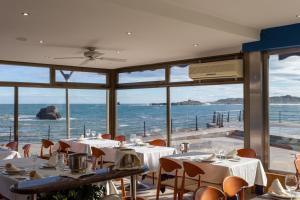 - un restaurant avec des tables et des chaises et une vue sur l'océan dans l'établissement Hotel Astuy, à Isla