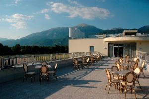 uma fila de mesas e cadeiras numa varanda com montanhas em Hotel Krek Superior em Lesce