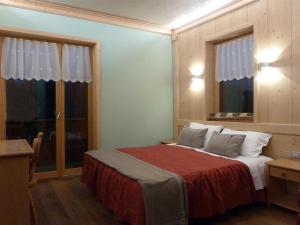 a bedroom with a bed with a red blanket and two windows at Albergo Chalet Lago Antorno in Misurina