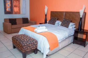 een slaapkamer met een groot bed met een oranje muur bij Coyotes Hotel & Conference Centre in Nelspruit