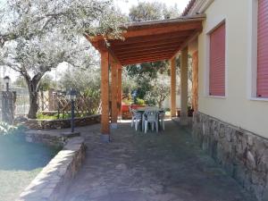 um pátio com uma mesa e cadeiras sob uma pérgula de madeira em Villa San Gavino em Budoni