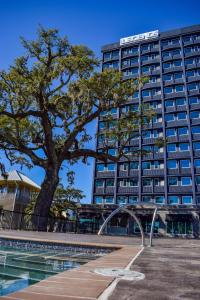 a tall building with a tree in front of a pool at Hotel Legends in Biloxi