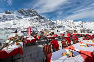 un restaurant avec des tables et des chaises en face d'une montagne dans l'établissement Hotel Enzian, à Zürs