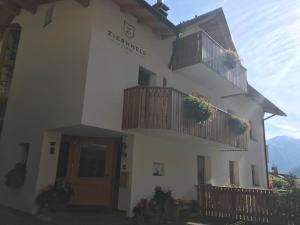 a white building with balconies and flowers on it at Garni Ziernheld in Malles Venosta