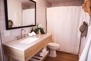 bagno con lavandino, servizi igienici e specchio di The Surfbreak Hotel a San Clemente