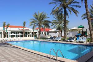 una piscina en un complejo con palmeras en Royal Residence Hotel Apartments, en Umm Al Quwain