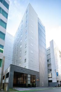 um edifício branco alto com muitas janelas em HOTEL FORZA HAKATAEKI CHIKUSHIGUCHI Ⅱ em Fukuoka