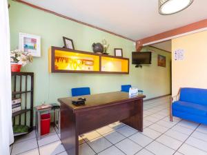 een kamer met een bureau, blauwe stoelen en een tv bij Hotel Posada San Rafael in Oaxaca City