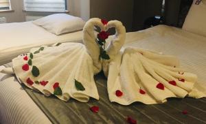 dos cisnes vestidos con toallas sentados en una cama en Homestay Hotel Heathrow, en Hounslow