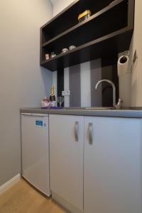 a kitchen with white cabinets and a sink at Apartments Slana Oaza in Tuzla