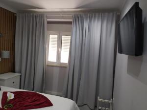 a bedroom with a bed and a window with curtains at Casa da Leninha in Nazaré