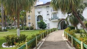 a walkway in front of a white house with palm trees at SandCastles Holiday #C9 in Ocho Rios