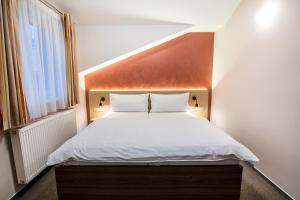 a bedroom with a white bed with a wooden headboard at Pension Bed&Breakfast in Kutná Hora