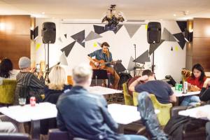 Un groupe de personnes assises à des tables avec un homme jouant de la guitare dans l'établissement Safestay London Elephant & Castle, à Londres