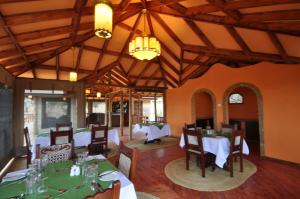 een eetkamer met tafels en stoelen en een kroonluchter bij Elephant Rock Luxury Camp Tarangire in Kaiti