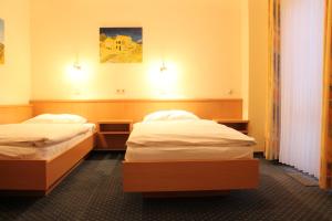 2 Einzelbetten in einem Zimmer mit 2 Lampen in der Unterkunft City Hotel Neuwied in Neuwied