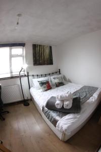 una camera da letto con letto, lenzuola e cuscini bianchi di College Street Abode a Portsmouth