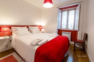 een slaapkamer met een wit bed en een rode deken bij Casa do Silverio - Barroca in Barroca