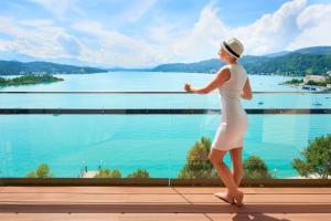 Una donna con un vestito bianco che guarda l'acqua di Parkhotel Pörtschach - Das Hotelresort mit Insellage am Wörthersee a Pörtschach am Wörthersee