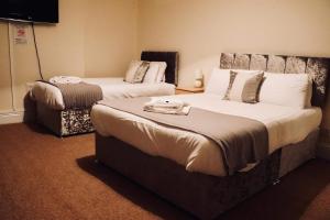 a hotel room with two beds and a tv at The New Alexandra Hotel in Llandudno