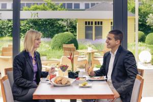 a man and woman sitting at a table at Mercure Hotel Mannheim am Rathaus in Mannheim