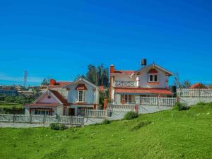 ein Haus auf einem grünen Hügel in der Unterkunft Pine View Stay Ooty in Udagamandalam