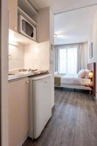 une cuisine et une chambre avec un lit dans une pièce dans l'établissement Residhotel Grenette, à Grenoble