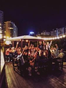 um grupo de pessoas com as mãos no ar em The Trip Hostel em Punta del Este