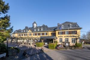 un grande edificio giallo con alberi di fronte di Jagdschloss Hotel Niederwald a Rüdesheim am Rhein