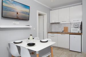 a white kitchen with a white table and chairs at Niko's Sea View Apartments Deluxe in Nesebar