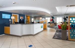 a man standing at a counter in a lobby at Holiday Inn Express Southampton West, an IHG Hotel in Southampton