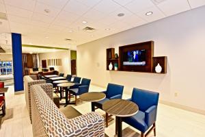 una sala d'attesa con tavoli, sedie e TV di Holiday Inn Express & Suites - Perryville I-55, an IHG Hotel a Perryville