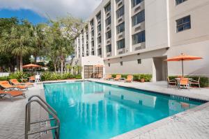 uma piscina num hotel com cadeiras e guarda-sóis em Holiday Inn Express Hotel & Suites Ft. Lauderdale-Plantation by IHG em Plantation