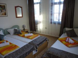 two beds in a room with two windows at Guest House Zhelevi in Sozopol