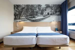 - une chambre avec 2 lits et un tableau mural dans l'établissement Aparthotel Campus, à Oviedo