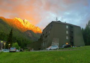 een gebouw met auto's geparkeerd voor een berg bij Hotel Alpina in Kranjska Gora