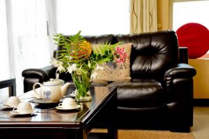 ein schwarzes Ledersofa mit einem Tisch mit einer Vase Blumen in der Unterkunft Lake View Apartments in Luzira