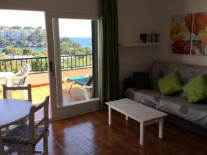 uma sala de estar com um sofá, uma mesa e uma varanda em Apartamentos Encanto Del Mar em Cala Galdana