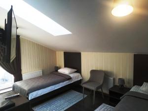 een slaapkamer met een bed, een tv en een stoel bij Hotel Business Apartments in Dnipro