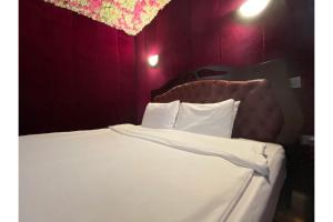 Un dormitorio con una cama blanca con paredes moradas en SK Baylis House Hotel, en Slough