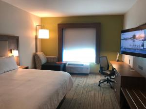 Holiday Inn Express & Suites Raleigh Airport - Brier Creek, an IHG Hotel في رالي: غرفة فندقية بسرير وتلفزيون بشاشة مسطحة