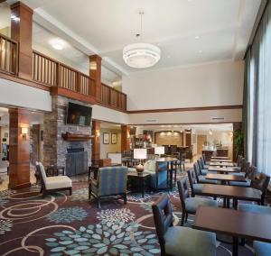 - une cheminée dans le hall de l'hôtel avec des tables et des chaises dans l'établissement Staybridge Suites Fayetteville, an IHG Hotel, à Fayetteville