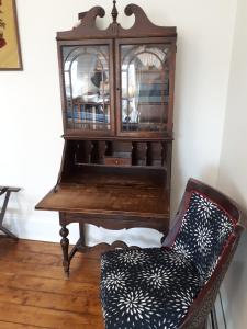 a chair next to a wooden cabinet with a mirror at Hillside Landing B&B in Digby