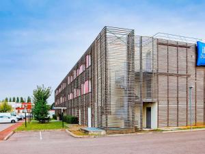 a large building with a metal facade on a street at ibis budget Metz Technopole in Metz