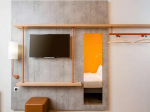 a room with a tv on a wall at ibis budget Metz Technopole in Metz