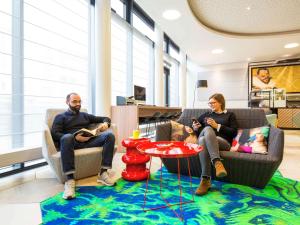 a man and a woman sitting in chairs in a room at Aparthotel Adagio Köln City in Cologne