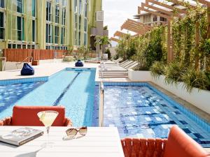 - une piscine avec des tables et des chaises à côté d'un bâtiment dans l'établissement Crystalbrook Bailey, à Cairns