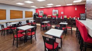 un restaurant avec des murs rouges, des tables et des chaises rouges dans l'établissement Chicago Southland Hotel, à Oak Forest