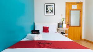 um quarto com uma cama branca e almofadas vermelhas em RedDoorz @ Arimbay Legazpi City em Legazpi